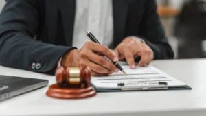 Avvocato che firma un documento legale su scrivania con martelletto del giudice